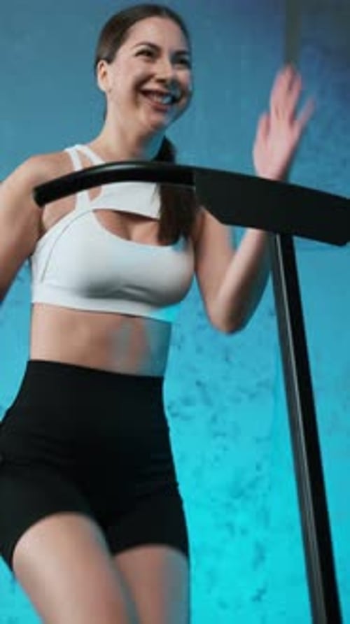 Close-up of legs of energetic young fitness girl in white sneakers jumping on mobile mini trampoline
