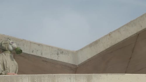 Man in Hazmat Suit Walks around Concrete Building