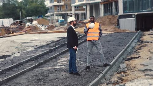 Two Men Discussing Construction Project at Outdoor Site