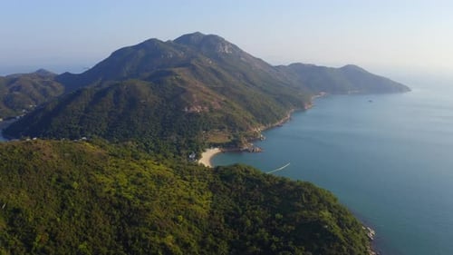 Cinematic drone shot traveling forward and panning down toward a beach on the coast of a tropical is