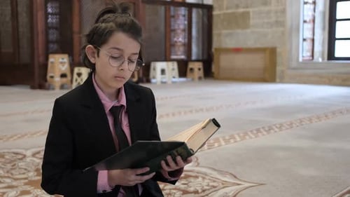 Young Person Reading Religious Book in Mosque