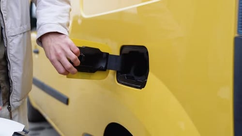 Die Hand eines Mannes bereitet sich darauf vor, ein Elektroauto aufzuladen