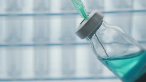 Syringe Drawing Turquoise Liquid from Glass Vial