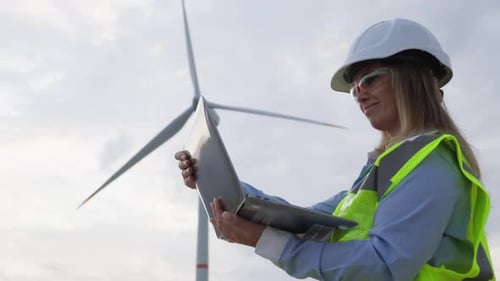 Engineer with a Laptop Near a Windmill Analysis of the Power of a Wind Turbine for Green Energy