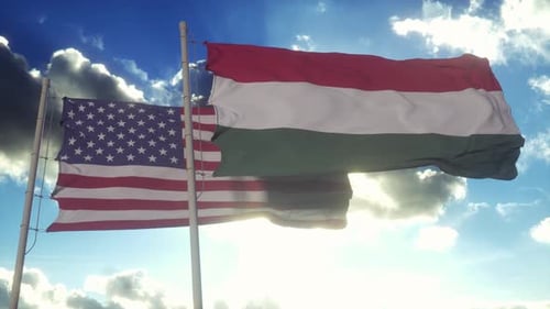 American and Hungarian Flags Waving Together Under Blue Sky