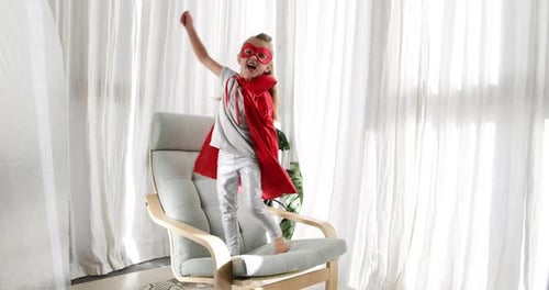 Girl in Red Cape Jumps on Armchair