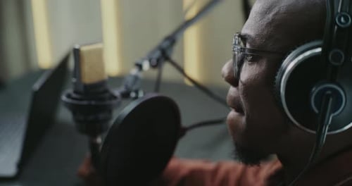 Man Wearing Glasses and Studio Headphones Speaking Energetically Into Pro Microphone