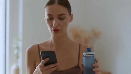Young Woman Hydrating While Using Mobile Phone