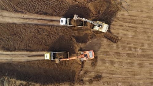 Excavators loading soil onto Trucks, Aerial view.