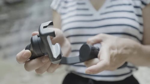 Close Up of Female Hands Holding Smartphone Tripod on Blurred Natural Background