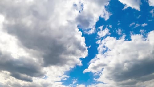 Two big clouds meet in the horizon forming one. Sky being covered with cloudscape. View from below.