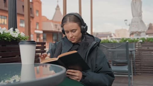 Cafe Reader Relaxing Outdoors Person with Headphones Enjoys City Terrace Silent Reader Wearing