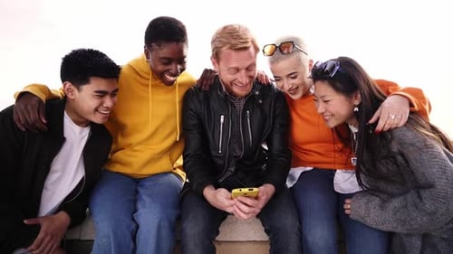 Smiling Friends Share Phone Together in Urban Setting