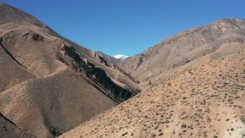 Imágenes con drones de un remoto paisaje montañoso con estribaciones marrones y una montaña cubierta de nieve en el Frank C.