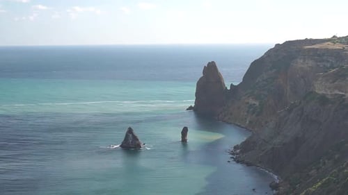 Vista aérea sobre el mar azul y las costas rocosas volcánicas: cúmulos esponjosos que se mueven en el brillante cielo del atardecer