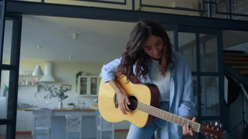 Young Woman Playing Acoustic Guitar in Modern Home