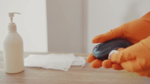 Sanitizing a Computer Mouse on Desk with Supplies