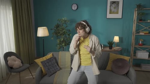 Man in Casual Clothing with Headphones on Dancing Like a Rock Star in the Living Room Listening to