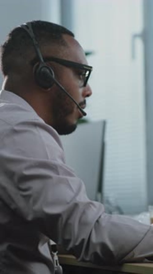 Side View of African American Hotline Operator Talking on Headset with Customer