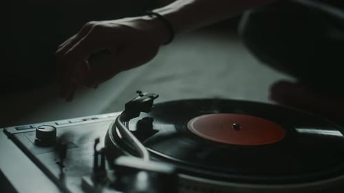 Unknown Young Man Putting on Vinyl Record and Turning on Player