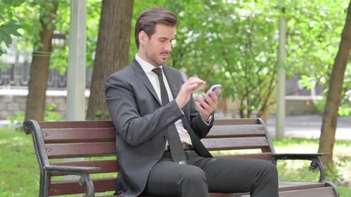 Man in Suit Using Smartphone on Park Bench