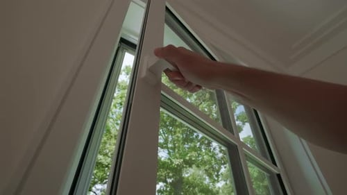 Arm Reaches to Open White Window Revealing Trees