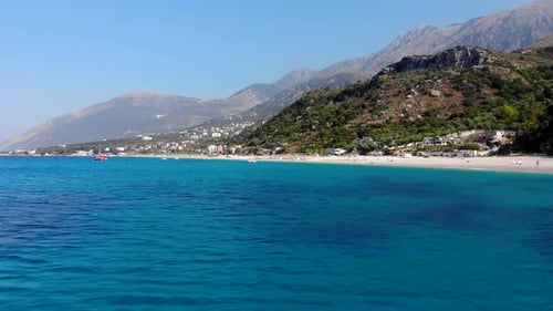 Blue azure sea water on rocky shoreline of Mediterranean with beautiful beach and mountains backgrou