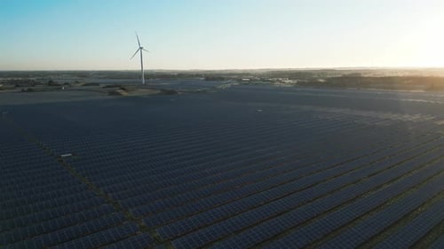 Aerial video shows synergy between wind turbines and solar panels generating renewable energy. The w