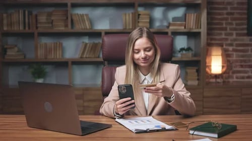 Woman Uses Credit Card and Phone at Desk