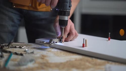 Man Attaches Hinge to Furniture with Power Drill