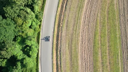 Aerial View of a Vintage Motorcycle Riding a Road Through Fields in Summer