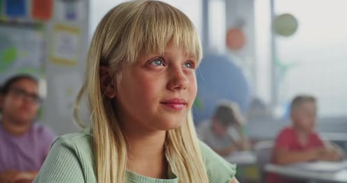 Close Up of Elementary School Girl Sitting at Desk Raising Hand and Answering Teacher's Question