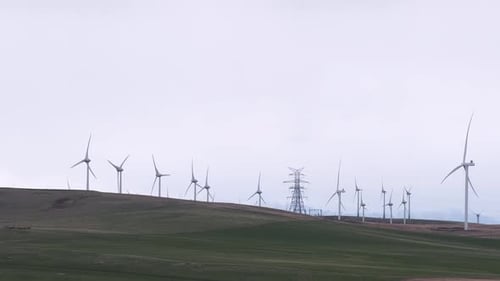 Windmühlen und riesiger Stromübertragungsturm in den Ausläufern der Rocky Mountains