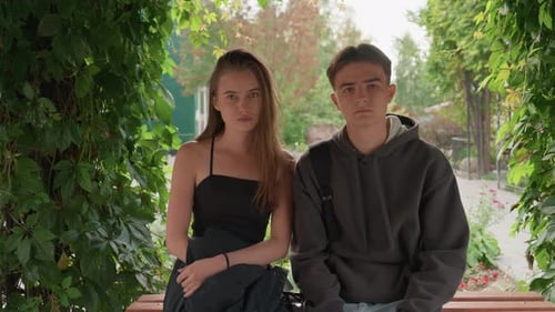 Young Adults Sitting on Bench Under Green Archway