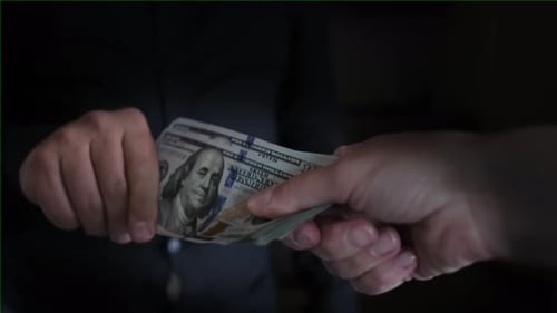 Pack of hundred dollar bills that two people pull on themselves and cannot share, close up