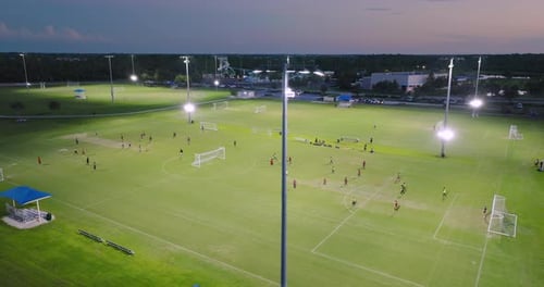 Sportsmen Playing Football Game on Illuminated Stadium in Public Sports Park