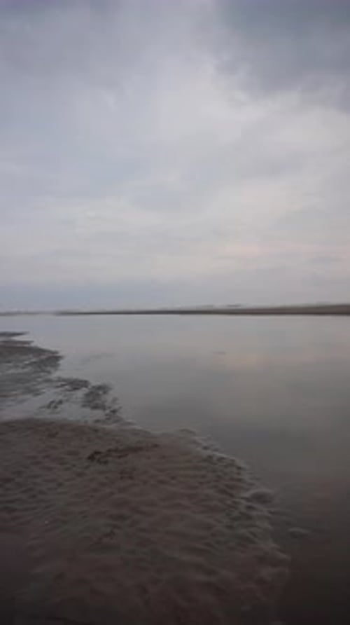 vertical beautiful beach portrait video view in the afternoon, you can see the small waves and the b