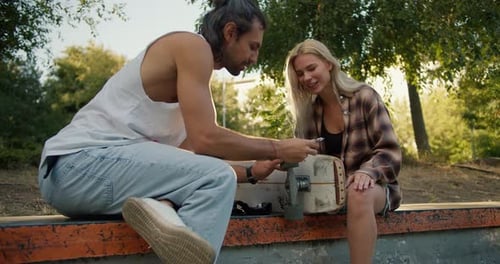 Young Couple Repairing Skateboard at Skate Park