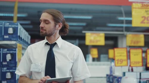 Attractive Man the Seller Work Use Tablet Computer Walk in Tech Department in Supermarket Feel Happy