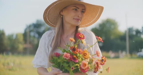 Happy Woman in Hat Holds Bouquet of Colorful Flowers