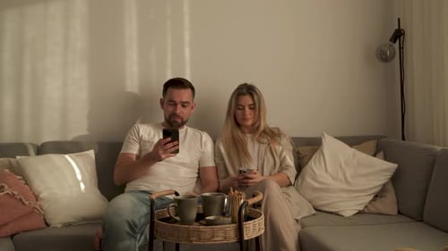 Cozy Couple Relaxing with Phones on Living Room Couch