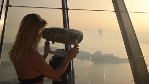 A Woman Stands on a Tall Building at the Palm Marina Bay Viewpoint in Dubai During Sunset