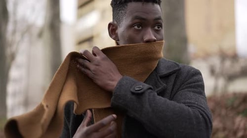 Man Adjusts and Wraps Scarf on Cold Day Outdoors