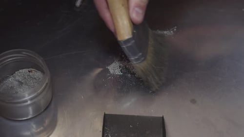 A Person is Brushing a Powdery Substance Onto a Surface