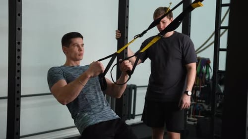 Muscular Fitness Instructor Male Showing Suspension Training to Motivated Beginner Young Man