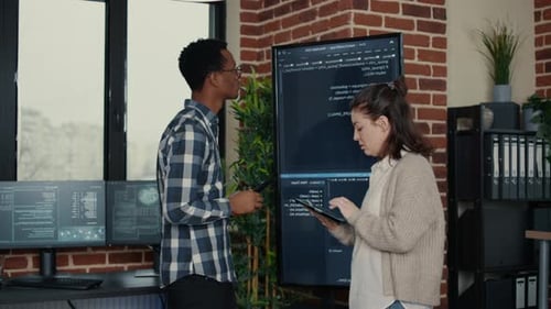 Softwareentwickler überprüft Debugging-Daten für Wandbildschirme mithilfe eines Tablets