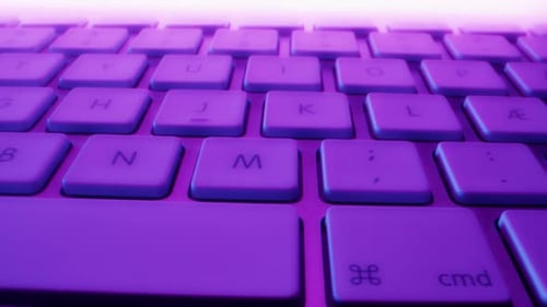 Nahaufnahme der Tasten der drahtlosen weißen und silbernen Tastatur in bunten Lichtern