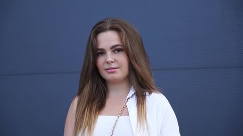 Portrait of young Caucasian girl in white shirt posing for camera. Close-up.