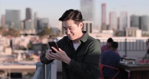 Smiling Man Using Phone on City Rooftop