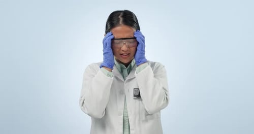 Stressed Woman in Lab Coat Rubbing Forehead